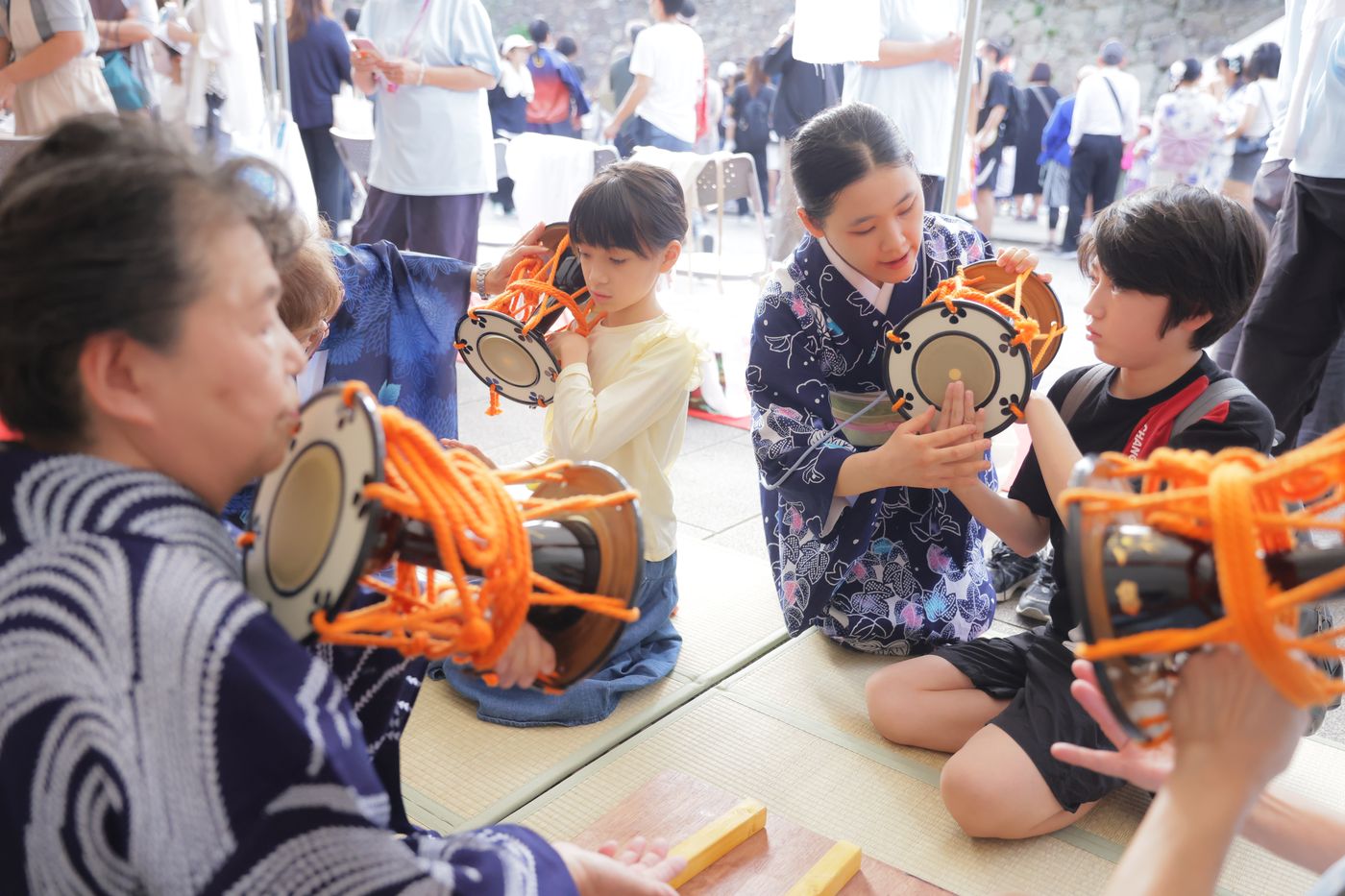 講師が子どもたちに小鼓の持ち方を教えている様子
