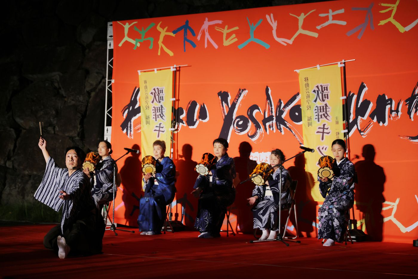 夜のステージで小鼓を手にした演者たちが並ぶ様子